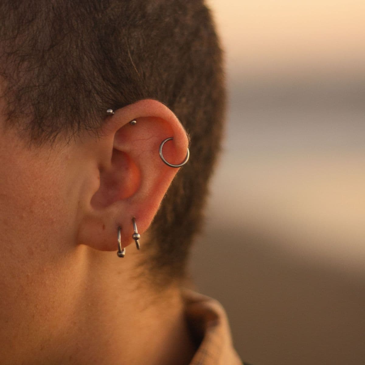 Close-up of an ear with rings in the lobe and the upper ear